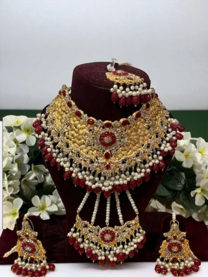 Heavy gold plated bridal jewelry set featuring a wide choker, earrings, and headpieces, all embellished with ruby red stones and white pearl drops.