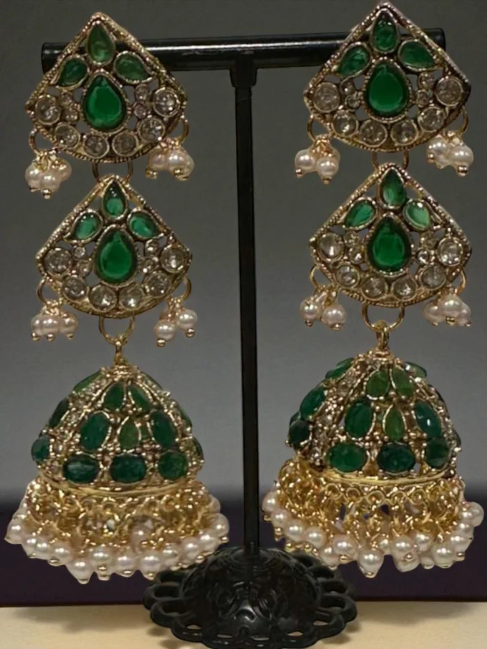 Antique gold plated multi-tiered jhumka earrings set with emerald green stones, clear crystals, and finished with a dense fringe of white pearl drops.