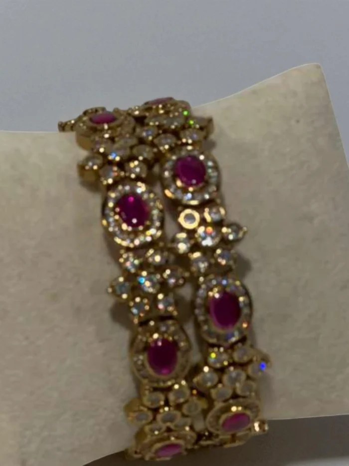 Pair of antique gold plated bangles set with oval ruby red stones and surrounding clear crystal flower clusters