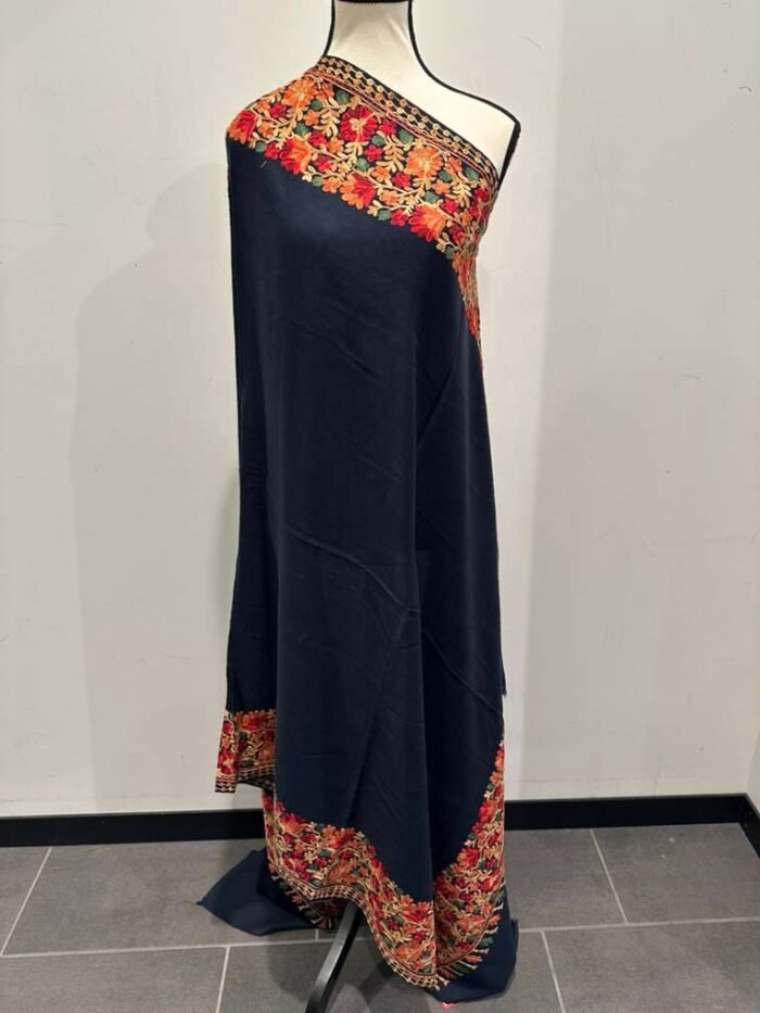 Long navy blue Kashmiri pashmina shawl with heavy, vibrant multi-color floral embroidery along the borders.