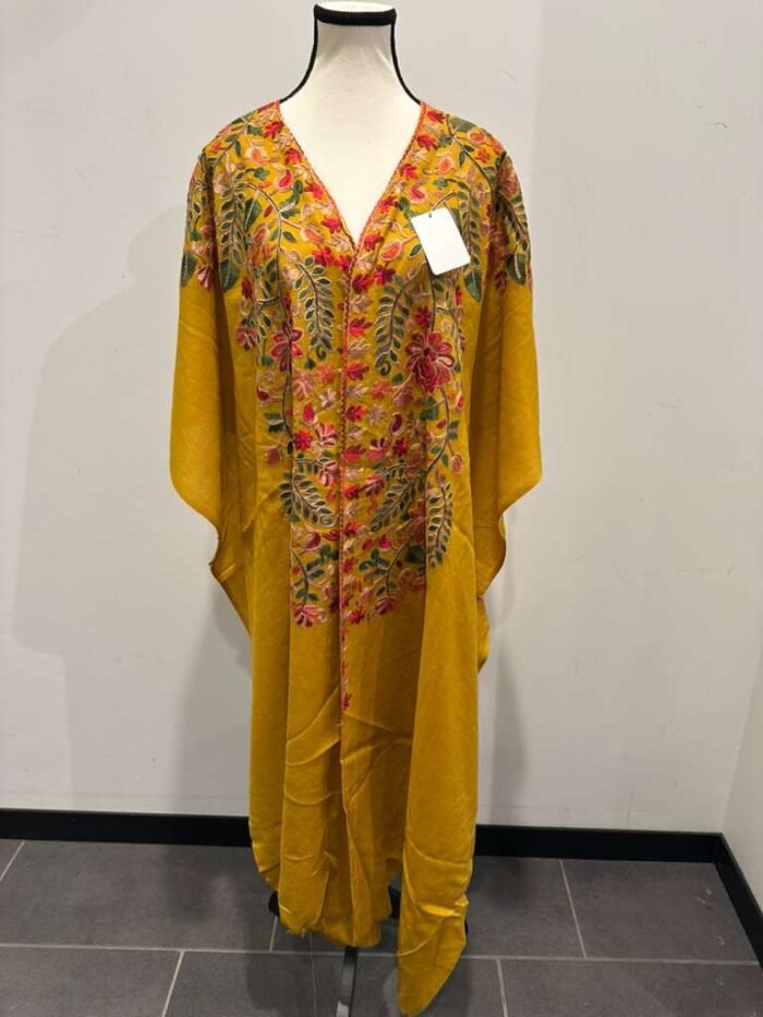 Mustard yellow pashmina cape shawl with a V-neck and heavy multi-color floral embroidery covering the chest and front opening.
