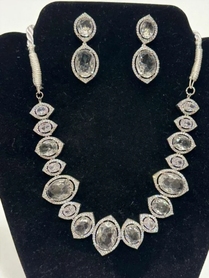 Clear AD stone and oval doublet stone necklace and earring set displayed on a black velvet jewelry display bust. The necklace forms a graduated V-shape.