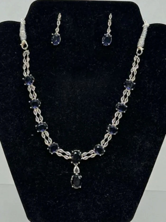 American Diamond necklace and earring set in silver polish with rich deep blue oval stones and clear AD accents, displayed on a black velvet jewelry bust.