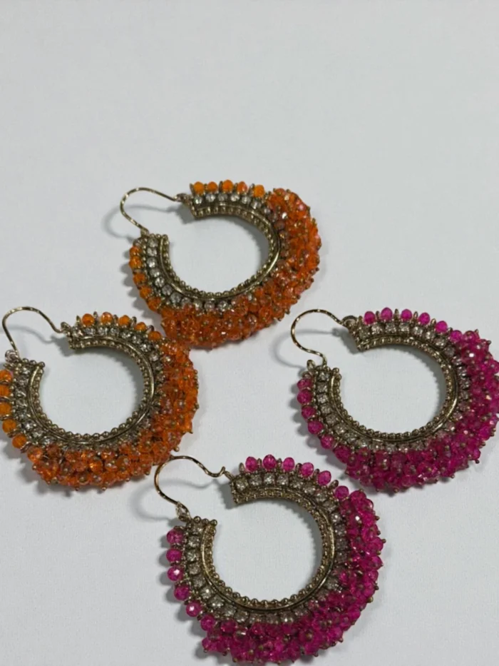 Two pairs of colorful beaded Bali hoop earrings, one pair in vibrant orange and the other in hot pink, featuring an antique metal finish and clear stone accents.
