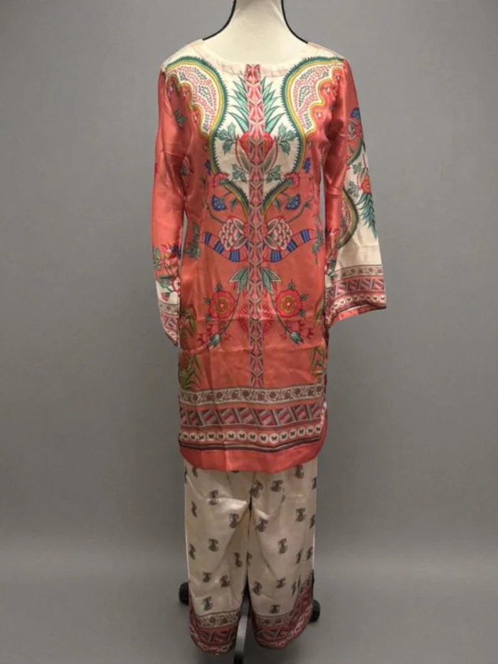 Silk Cord Set displayed on a mannequin. Features a vibrant coral tunic with a central ornamental print in pink, teal, and yellow, paired with light-colored printed trousers.